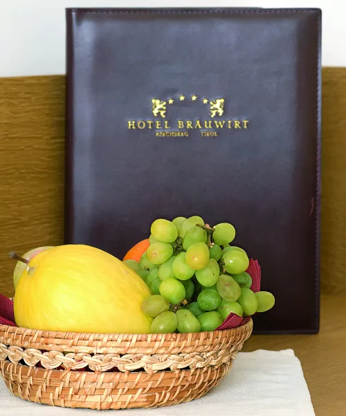 Obstschale mit Trauben und einem Apfel vor einer Speisekarte von Hotel Brauwirt