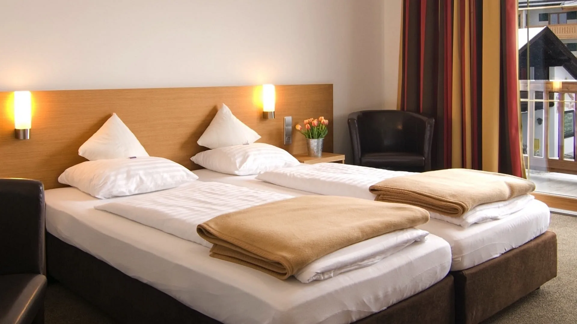 Ein Doppelzimmer mit zwei Betten, stimmiger Dekoration und Balkon.