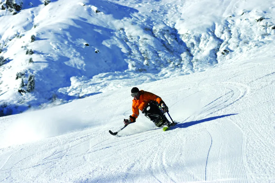 Skifahrer im Rollstuhl fährt auf einer verschneiten Piste