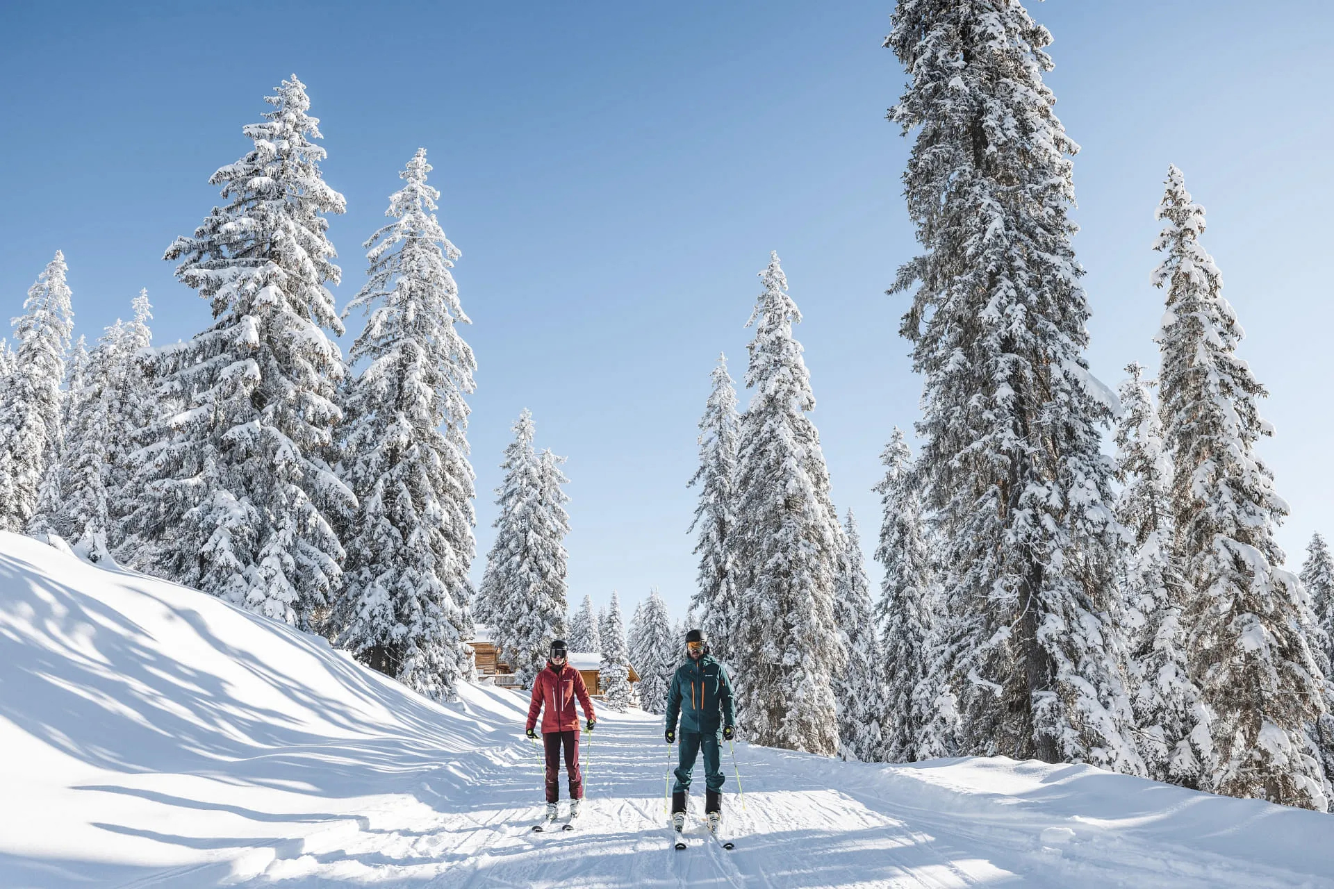 Zwei Skifahrer auf einer Schnee-Piste in winterlicher Berglandschaft