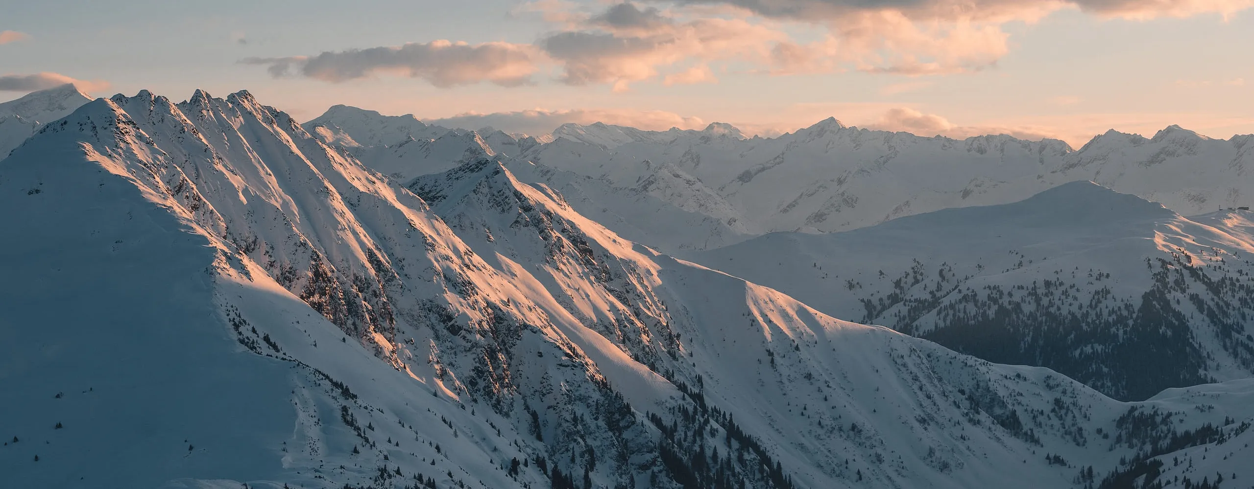 Schneebedeckte Berge mit sanften Wolken im Hintergrund bei Dämmerung
