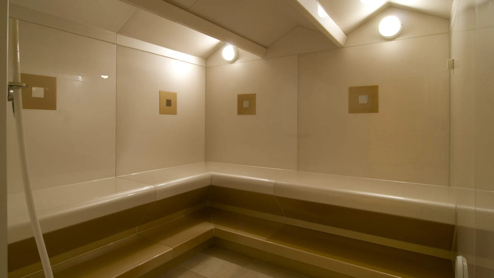  Innenansicht eines minimalistischen Dampfbades mit Beleuchtung und Sitzbänken.