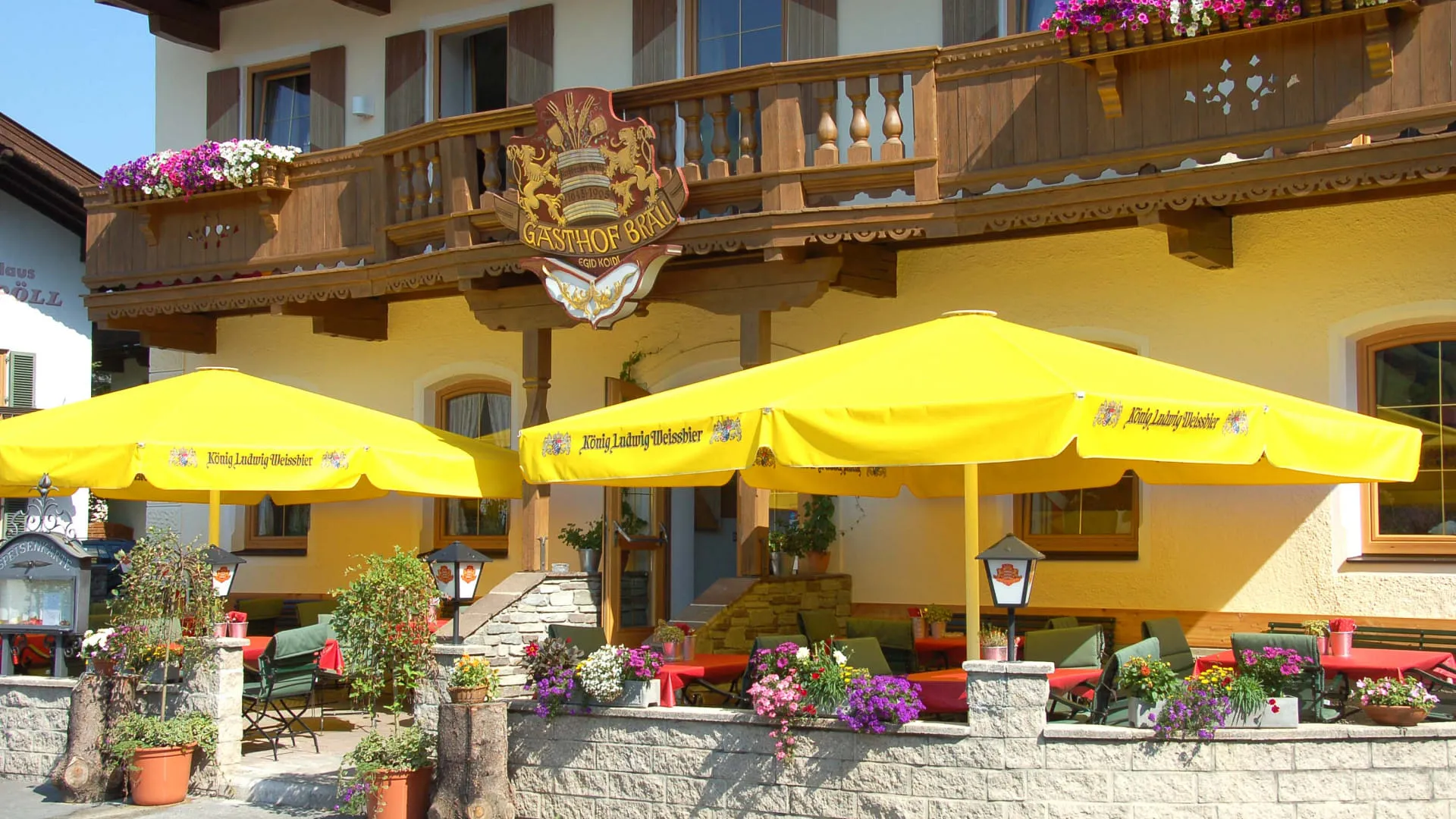 Gaststätte mit gelben Sonnenschirmen und Balkonblumen