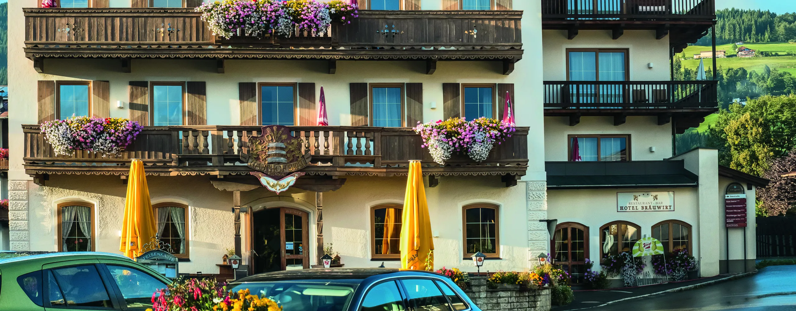 Blick auf ein Gebäude mit Balkonen, Blumen und Sonnenschirmen